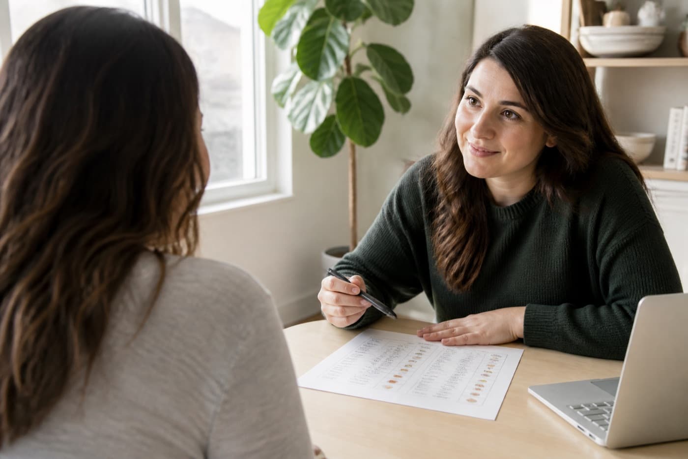 A dietitian listening across a table; the patient is seen from behind