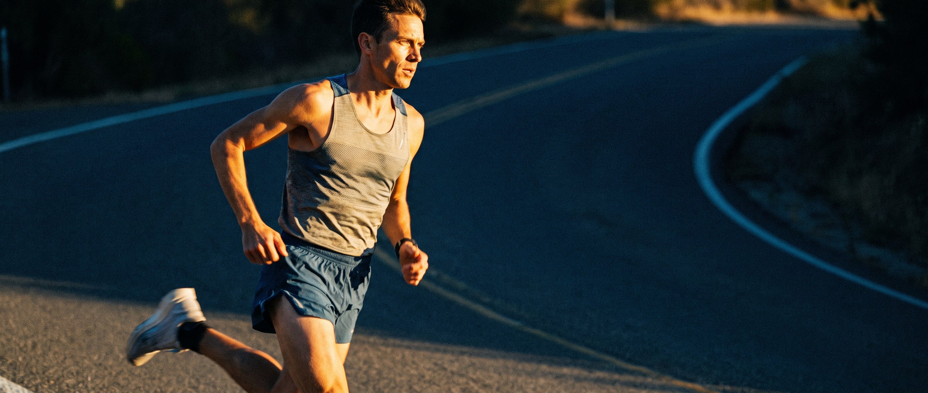 A runner on a winding road in low sun